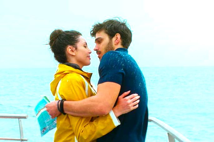 Casal se beijando num barco.